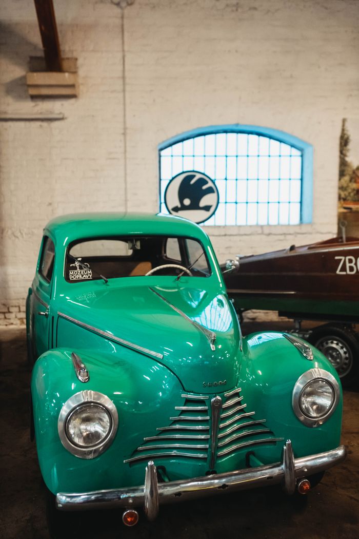 A vibrant green Škoda 1101 1102 vintage car displayed in a cozy indoor garage.