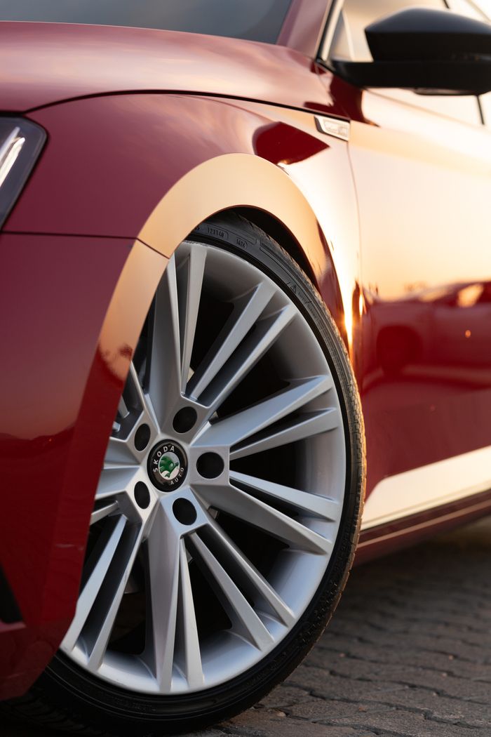 Detailed view of a red car's wheel reflecting a sunset glow, showcasing modern luxury.